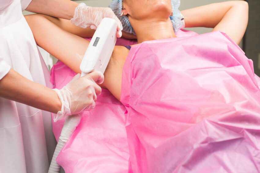 Spa, people and cosmetology concept - Woman having underarm laser hair removal epilation