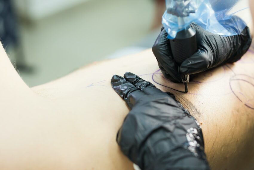 tattooer showing process of making a tattoo, hands holding a tatoo machine.