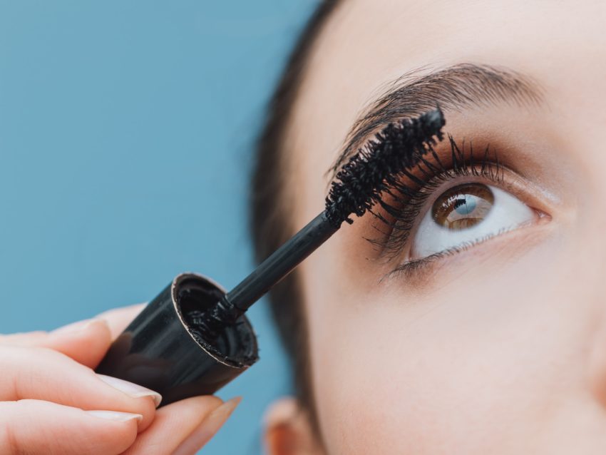 Woman applying mascara on her lashes
