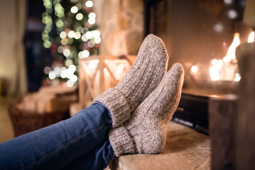 Feet of unrecognizable woman in socks by the Christmas fireplace.